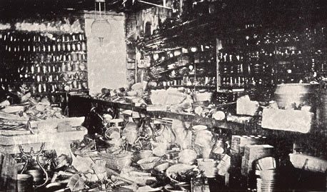 An interior view of one of the first Woolworth stores shows ramshackle displays made out of upturned packing cases. You can make out a number of different saucepans amond the products on sale.