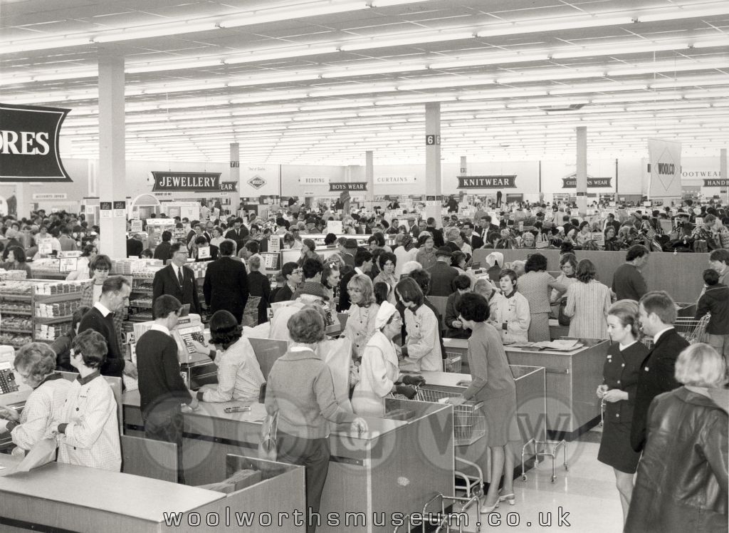 A panorama of the huge 68,000 square foot salesfloor at Woolco, Thornaby viewed the checkouts at the front of the store. NCR electo-mechanical cash registers jangle, with the Jewellery, Fashion and Textile Departments all in view through the throng of shoppers.